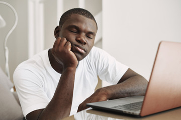 A man of African appearance at home in front of a laptop relaxing