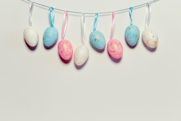 Decorative easter eggs hanging on a strip next to white background.