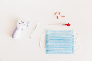 Medical protective mask with a thermometer on white background with pills. A disposable surgical face mask. Healthcare and medical concept.
Prevention of the Covid-19 pandemic virus. Quarantine.
