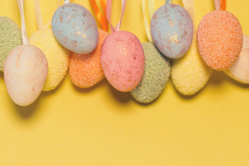 Decorative easter eggs hanging on a strip next to colorful pastel background.
