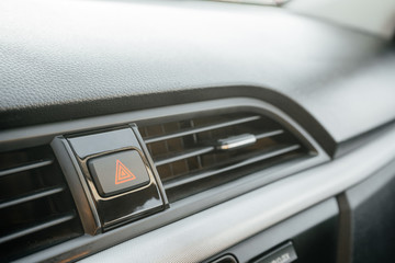 Closeup on emergency button with red triangle icon on car dashboard. The concept of a problem, stop, accident or damage.