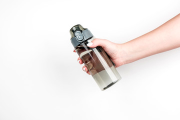 Sports water bottle in a woman's hand on a light background