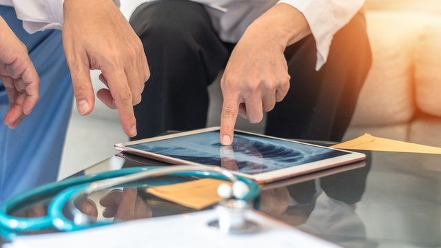COVID-19 and doctor teamwork diagnosing lung infection disease on x-ray in digital tablet with ER surgery medical team working in hospital discussing on patient care operation and treatment