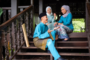 A group of malay muslim people in traditional costume having happy conversation during Aidilfitri...