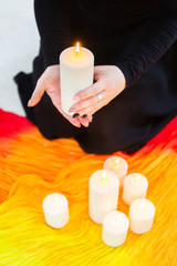 Female hands hold a lighted candle in the dark at night. A fortune teller performs a magical. Ritual of enchantment and clairvoyance. Seance and prediction of the future