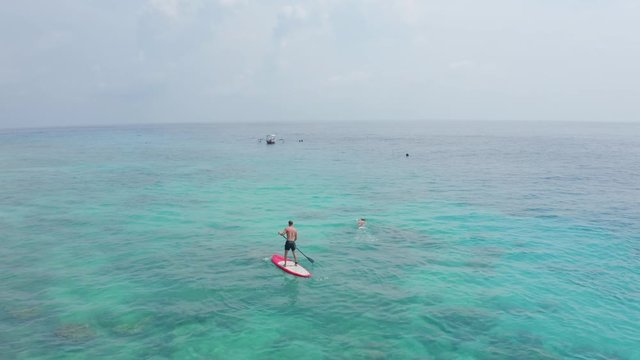 flycam films fit man practising Stand Up Paddle on ocean
