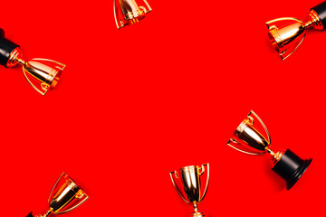 Winner cups on a red background with copy space. Flat lay style.