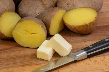 boiled potatoes on a wooden board and butter with a knife
