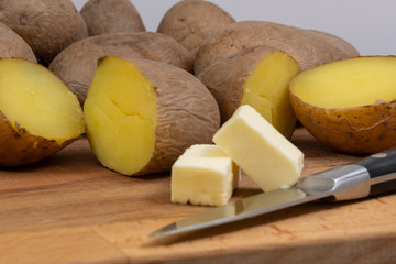 boiled potatoes on a wooden board and butter with a knife