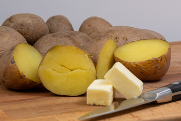 boiled potatoes on a wooden board and butter with a knife