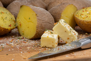 boiled potatoes on a wooden board and butter knife and spices salt and pepper