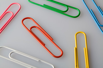 multi colored paper clips on a white, gray background