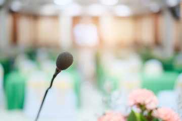 Close up microphone attached in stand on stage, concept of giving presenting and speech discussing in seminar or conference in business and company event, with blur abstract background in hall room