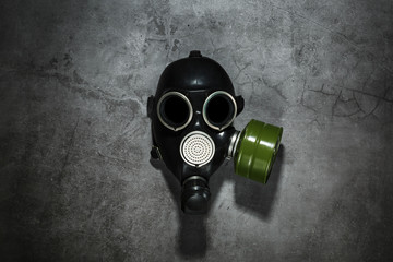 Gas mask on a black stone background with a green filter cartridge. Post-apocalyptic concept.