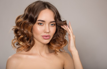 Fototapeta premium Portrait of a young fashion woman. Voluminous wavy hair. A hand near her face. on white background