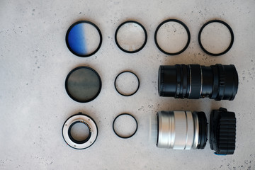 Two lenses and filters to them, adapter rings and a box with flash drives on grey backgrond. Flat lay composition with equipment for photographer