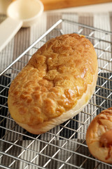 Homemade baked bakery or dessert, a variety of Hong Kong style bread or bun place on a cooling rack on striped placemat and some ingredients such as egg and utensils around it