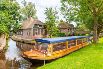 Empty canal cruise boat in front of old houses in the village of Giethoorn, The Netherlands
