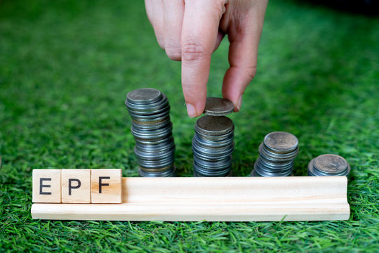 Wooden blocks spelling EPF with a stack of coins growing in size set on grass