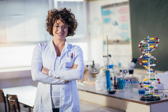 Young scientist posing in the lab with big model of a DNA chain.