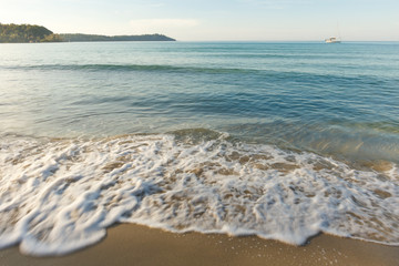 Smooth of sea wave above white sand in the morning.