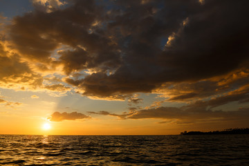 Seascape at Sunset time with nimbus clouds showing the orange sky in low light.