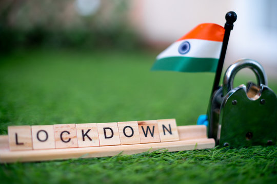 Wooden blocks set on grass with the text Lockdown on them with a shiny silver lock and a small indian flag on the side