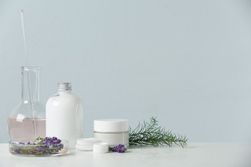 Herbal cosmetic products, laboratory glassware and ingredients on white table, space for text