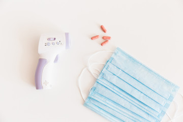 Medical protective mask with a thermometer on white background with pills. A disposable surgical face mask. Healthcare and medical concept.
Prevention of the Covid-19 pandemic virus. Quarantine.