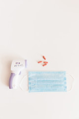 Medical protective mask with a thermometer on white background with pills. A disposable surgical face mask. Healthcare and medical concept.
Prevention of the Covid-19 pandemic virus. Quarantine.