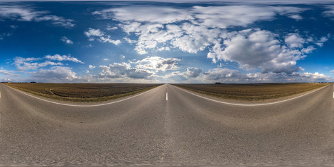 Full spherical seamless panorama 360 degrees angle view on no traffic asphalt road among fields in spring day with cloudy sky. 360 panorama in equirectangular projection, VR AR content