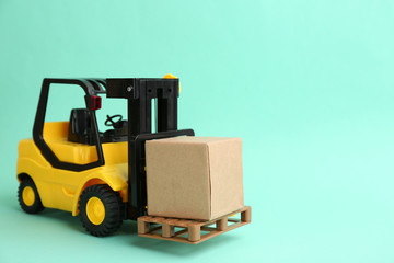 Forklift model and carton boxes on turquoise background, space for text. Courier service