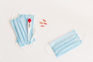 Medical protective mask with a thermometer on white background with pills. A disposable surgical face mask. Healthcare and medical concept.
Prevention of the Covid-19 pandemic virus. Quarantine.