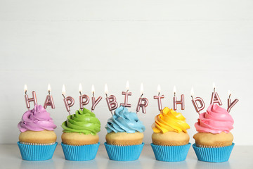 Birthday cupcakes with burning candles on table against white background. Space for text