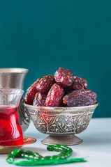 Dry medjoul dates in a vintage bowl with turkish tea in a glass.