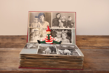 old retro album with monochrome photos in sepia color and vintage wooden toy clown, concept of...