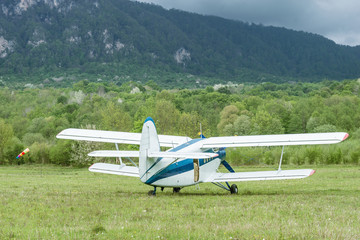 Old retro plane stands on mountain background.