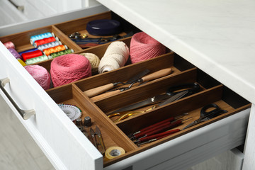 Fototapeta na wymiar Sewing accessories in open desk drawer indoors