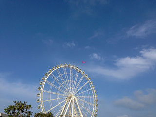 Noria de feria en el puerto de valencia con una cometa volando