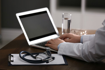 Professional doctor working on laptop in office, closeup
