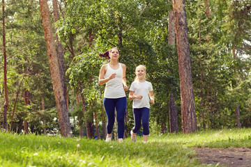 Naklejka na ściany i meble running sporty mother and daughter. woman and child jogging in a park. outdoor sports and fitness family.