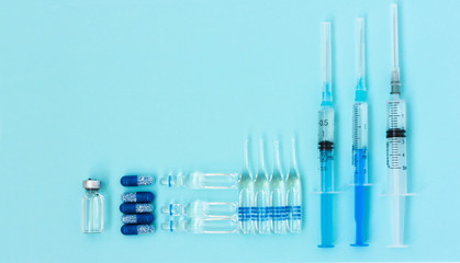 Thermometer, pills, injection ampoules, syringe for vaccination on a blue background, healthcare coronavirus, cancer, painand treatment, pharmaceutical medicine concept .