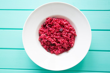 Obraz na płótnie Canvas Italian risotto with beetroot on turquoise table, top view. Vegetarian dish.