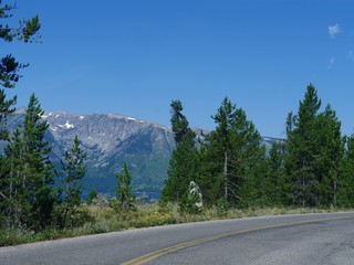 Scenic road view with pine trees and mountain ranges  at the Grand Teton National Park, Wyoming.