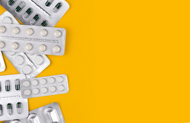 A variety of pills in blisters on a yellow background copy space. Medicines