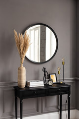 Console with a mirror on a background of a gray wall in a modern interior.