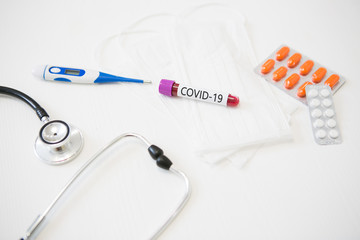 test tube with COVID-19 virus test along with medical devices, thermometer, masks, tablets