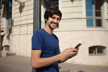 Young brunet man smiling speaking on the mobile phone walking down the street.