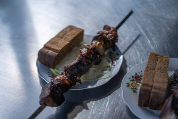 Skewers on a shopal in a plate with onions and bread