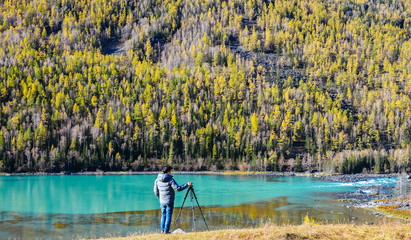 Obraz premium man enjoys peaceful view of Wolong Bay at Kanas Lake